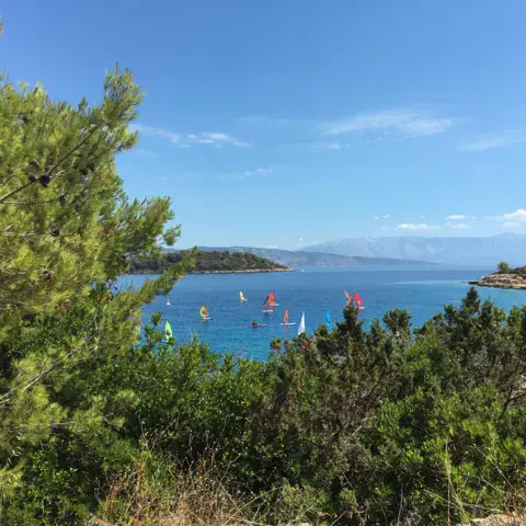 Baie avec voiles de windsurf au large, vue depuis la côte