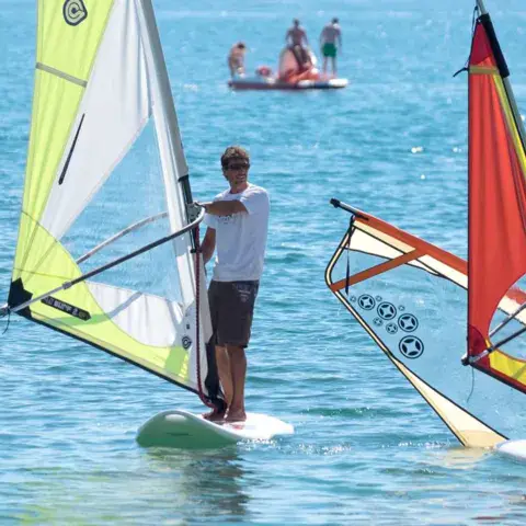 Élèves sur des planches à voile en eau peu profonde
