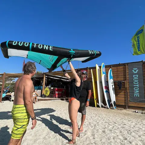 Préparation d'une aile Duotone sur la plage, devant la cabane du centre