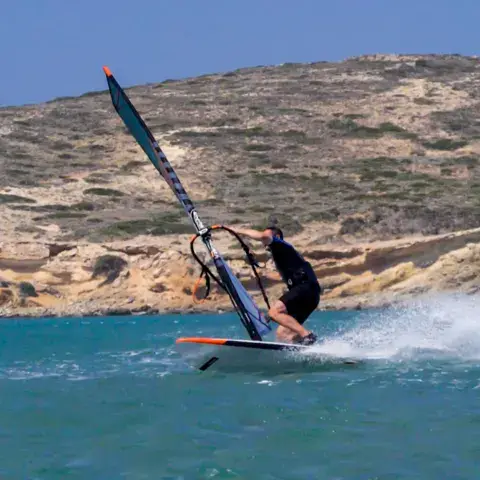 Windsurfeur en action devant un rivage rocheux