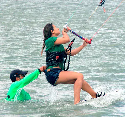 Élève de kitesurf en action avec un instructeur à côté
