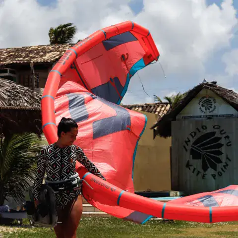 Kite rouge manipulé sur la pelouse devant les cabanes