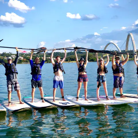 Groupe en stand up paddle, pagaies levées, sur le lac