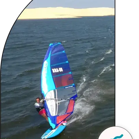 Windsurf vu du ciel sur un plan d'eau bordé de dunes