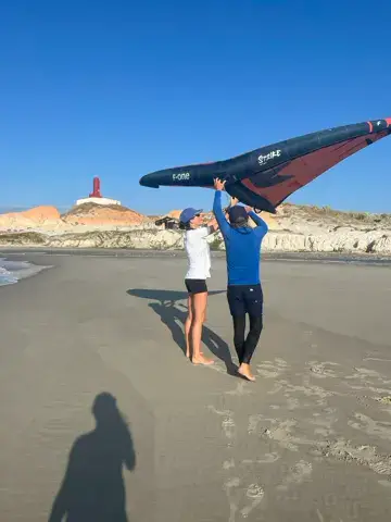 Deux personnes portant une aile près d'un phare