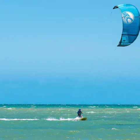 Kitesurfeur naviguant au large sous un kite bleu