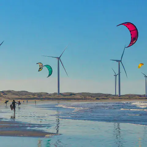 Kites sur une plage avec des éoliennes en arrière-plan