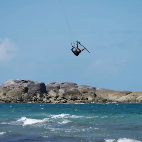 Kitesurfeur en saut devant des rochers