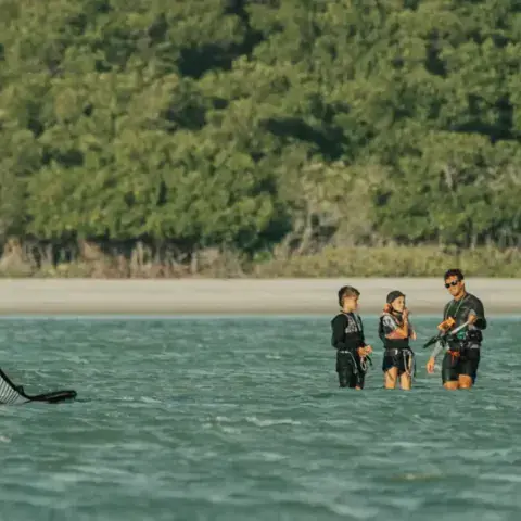 Cours de kite avec un instructeur et deux élèves dans l'eau