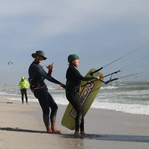 Deux personnes avec une aile de kite sur la plage