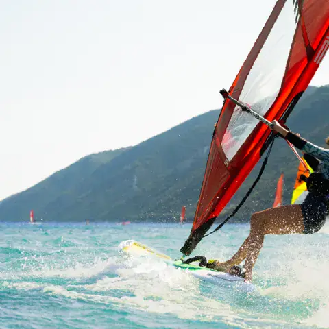 Windsurfeuse en navigation devant la côte