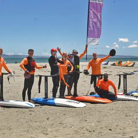 Équipe et élèves avec des planches sur la plage
