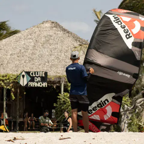 Base de kitesurf sous une paillote, kites posés sur le sable
