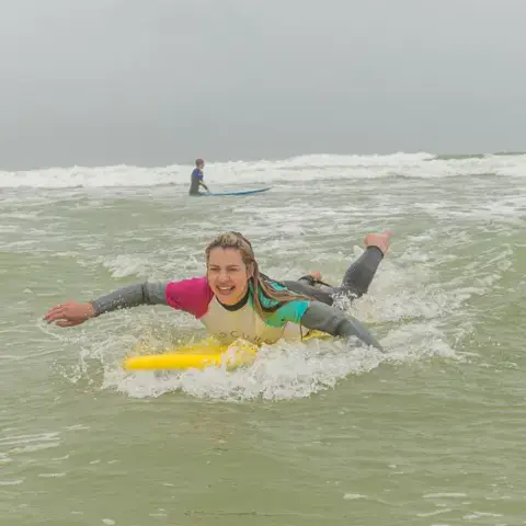 Élève allongée sur sa planche dans les vagues