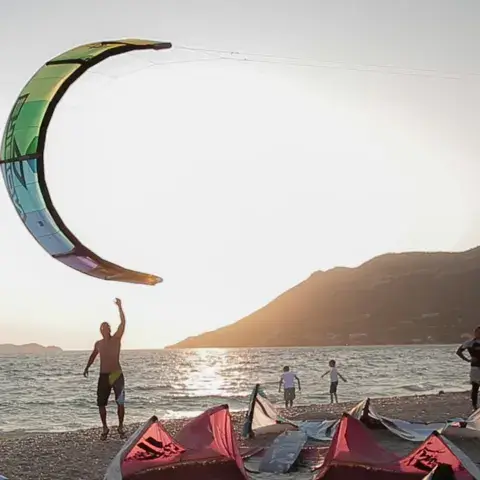 Kiteurs et ailes sur la plage au coucher du soleil