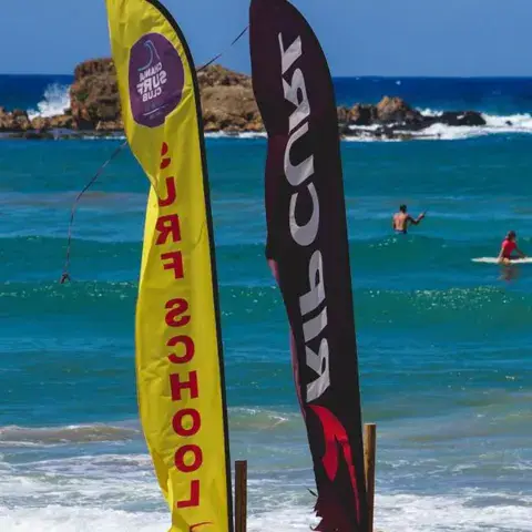 Oriflammes de l'école de surf plantées dans l'eau