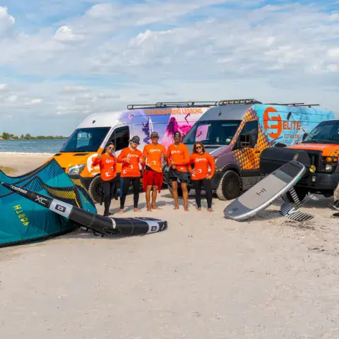 L'équipe sur la plage avec ses camionnettes et du matériel de kite et de foil