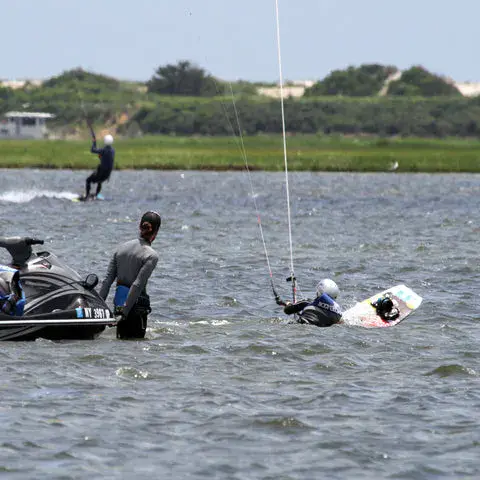 Élève dans l'eau avec sa planche et son aile, un jet-ski à proximité