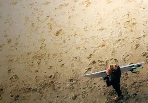 Surfeur marchant sur le sable avec sa planche