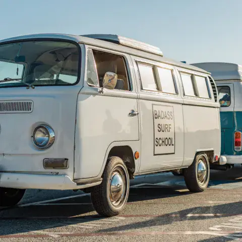 Le van de l'école et sa remorque sur le parking de la plage