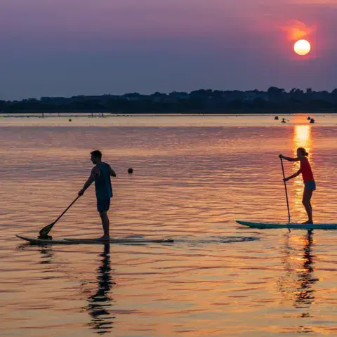 Deux pratiquants de stand up paddle au coucher du soleil