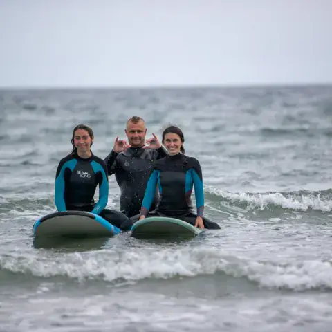 Trois surfeurs assis sur leurs planches dans l'eau