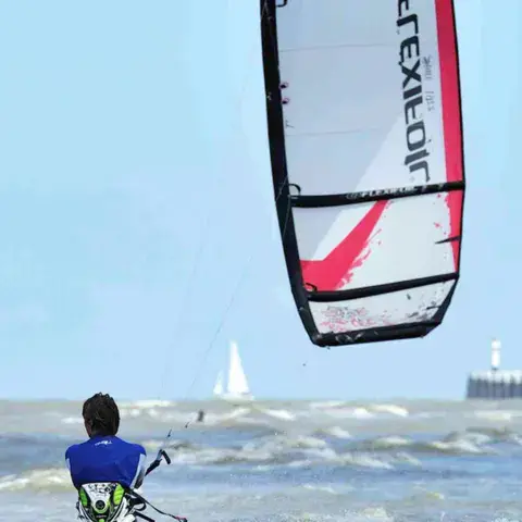 Élève de dos en kitesurf face à la mer