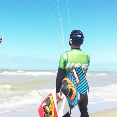 Élève en combinaison KSS sur la plage avec sa planche