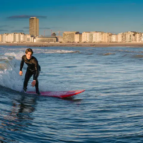 Surfeur sur une vague devant la plage d'Ostende