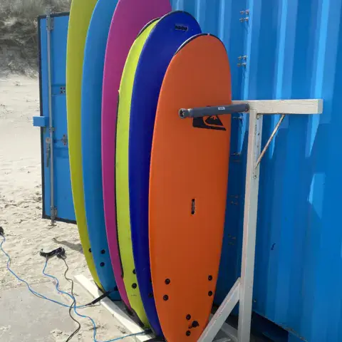 Planches de surf de location rangées dans leur râtelier