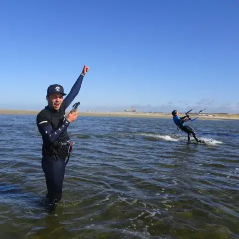 Moniteur dans l'eau à côté d'un élève en kitesurf