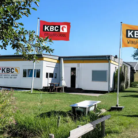 Bâtiment de l'école KBC avec les drapeaux kitesurf et wingfoil
