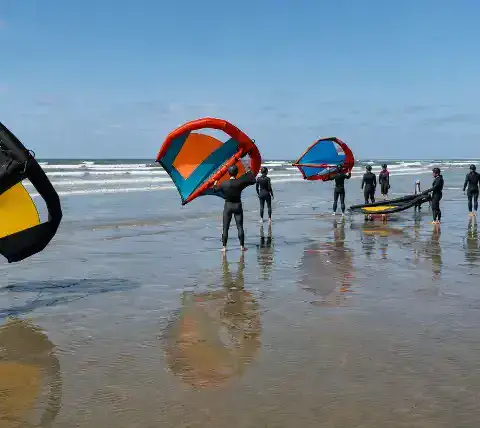 Groupe de wingfoil sur la plage, ailes en main