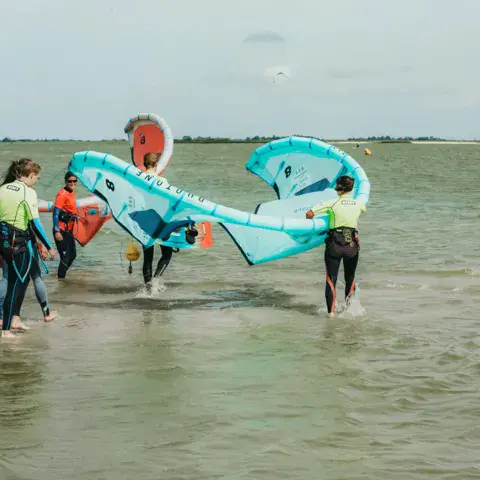 Groupe d'élèves avec leurs kites en eau peu profonde