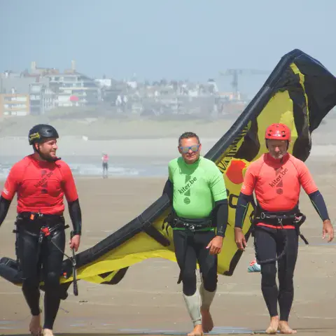 Moniteurs et élèves en tenue de kitesurf sur la plage