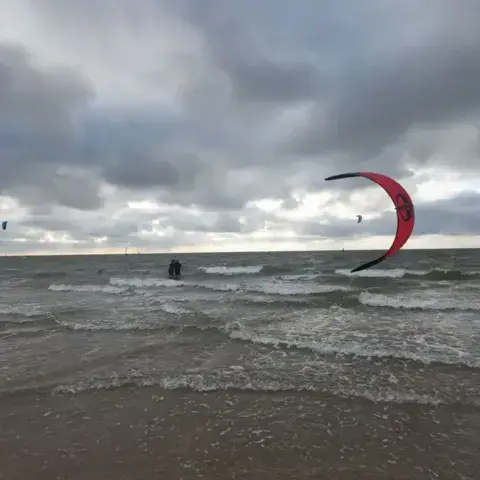 Kitesurfeur dans les vagues sous un ciel nuageux