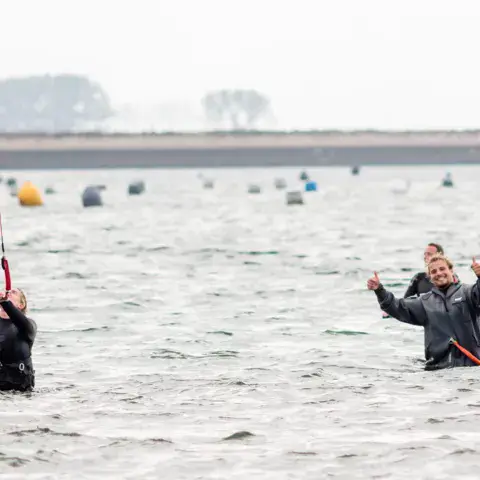 Élèves debout dans l'eau peu profonde avec leur kite