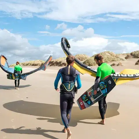 Deux riders marchant sur la plage avec ailes et planche