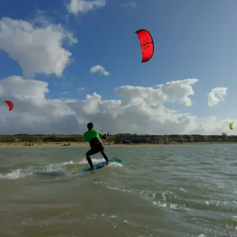 Kitesurfeur sur le plan d'eau, kites rouges dans le ciel