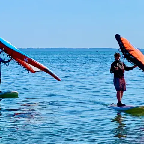 Élèves de wing sur leur planche, dans l'eau peu profonde