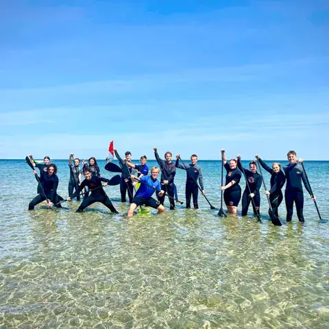 Groupe de stand up paddle dans l'eau peu profonde