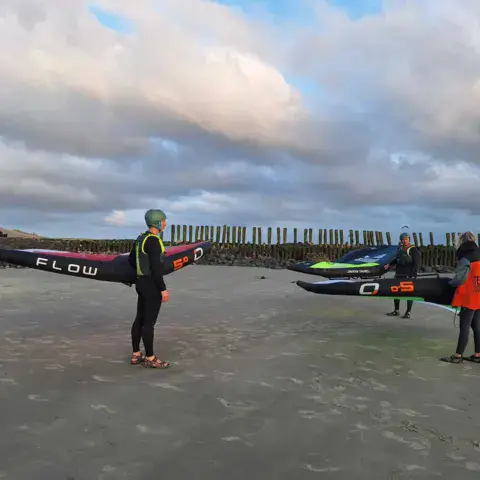 Élèves de wing avec leur aile et leur planche sur la plage