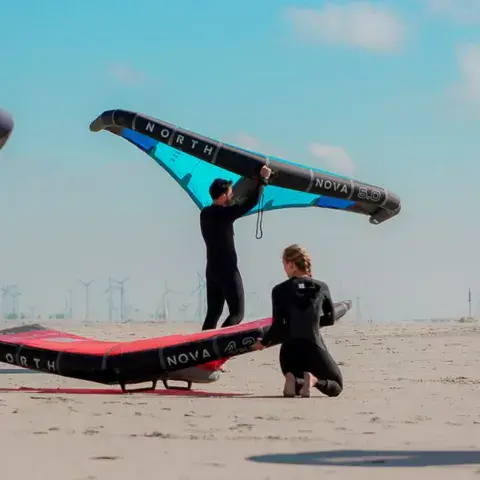 Préparation d'une aile de wing sur la plage