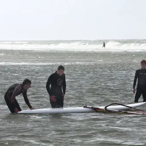 Moniteur et élèves avec une planche de windsurf