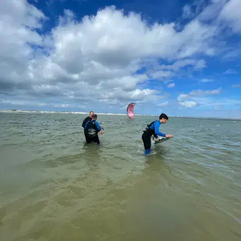 Élèves dans l'eau peu profonde, kite en l'air