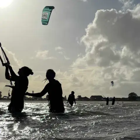 Cours de kitesurf dans l'eau, en contre-jour