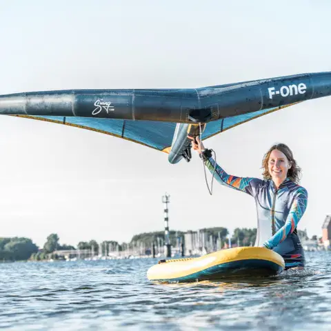 Une élève tient son aile sur un paddle