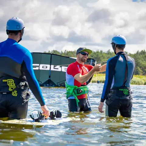 Moniteur de kite avec deux élèves dans l'eau