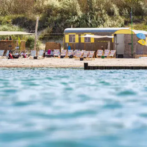 Bar de plage et bus jaune vus depuis l'eau