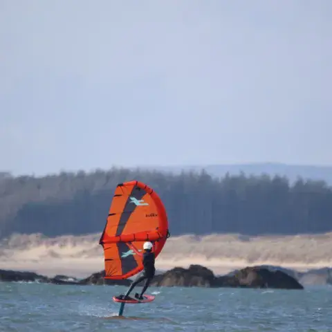 Rider de wing foil devant la côte rocheuse